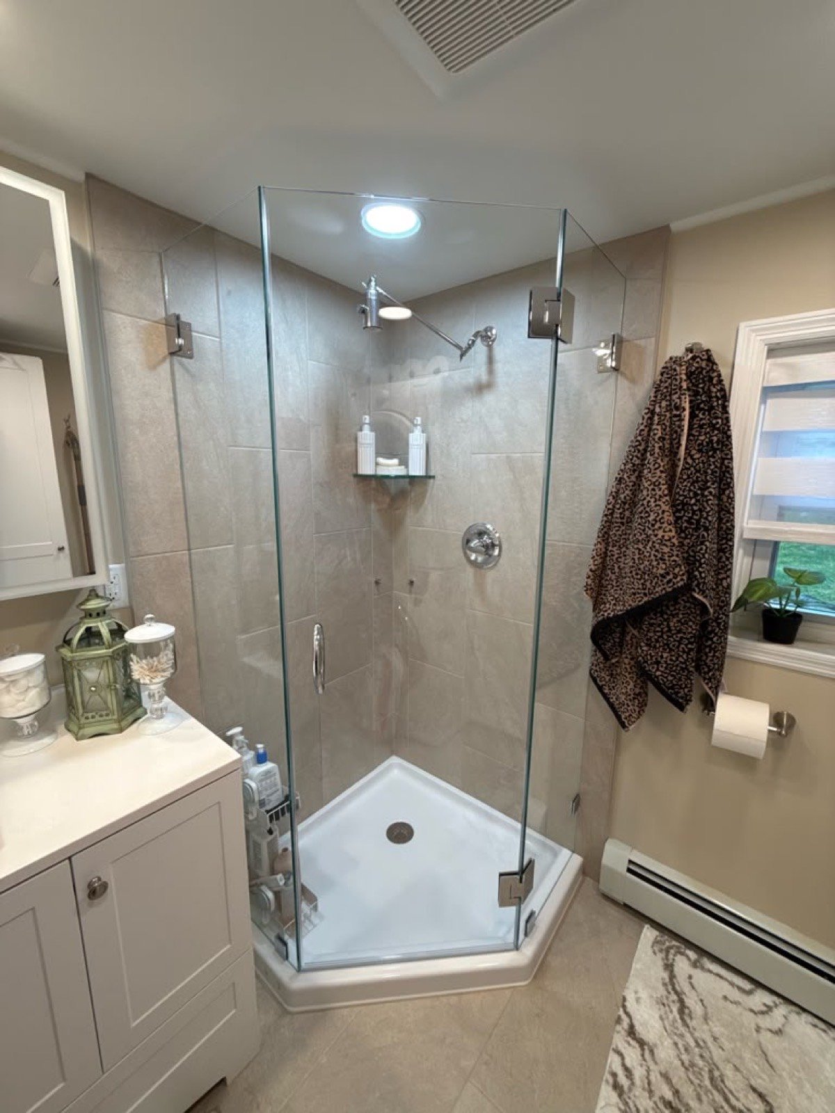 Corner glass shower with a recessed shower light in a renovated bathroom