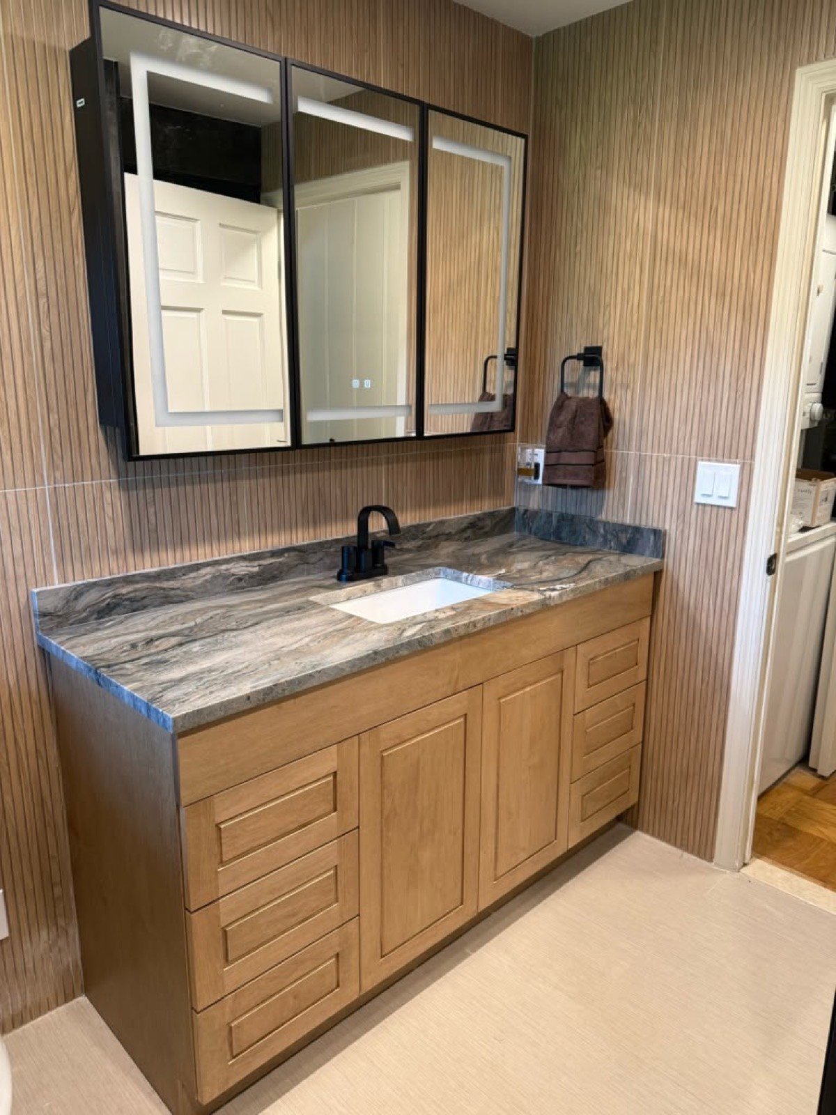Custom wood vanity with a stone countertop and backlit LED medicine cabinets
